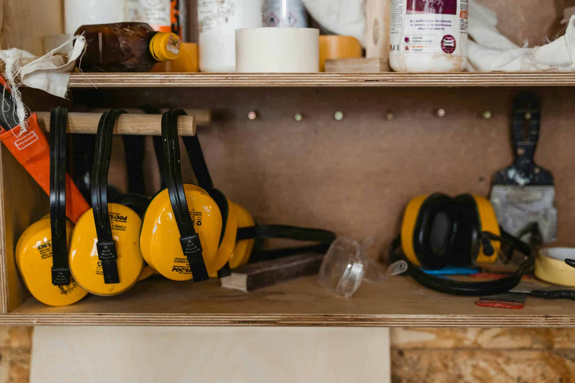 Hand tools and cleaning brushes hung neatly on a black pegboard inside a shed.