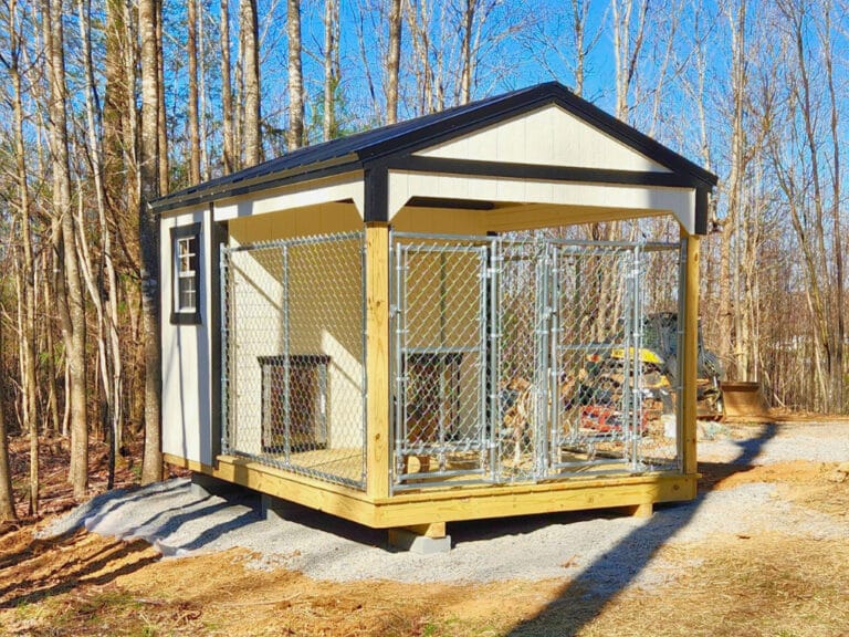 An outdoor dog kennel featuring a spacious covered shelter with chain-link fencing, a sturdy wooden base, and built-in dog houses in a wooded area.