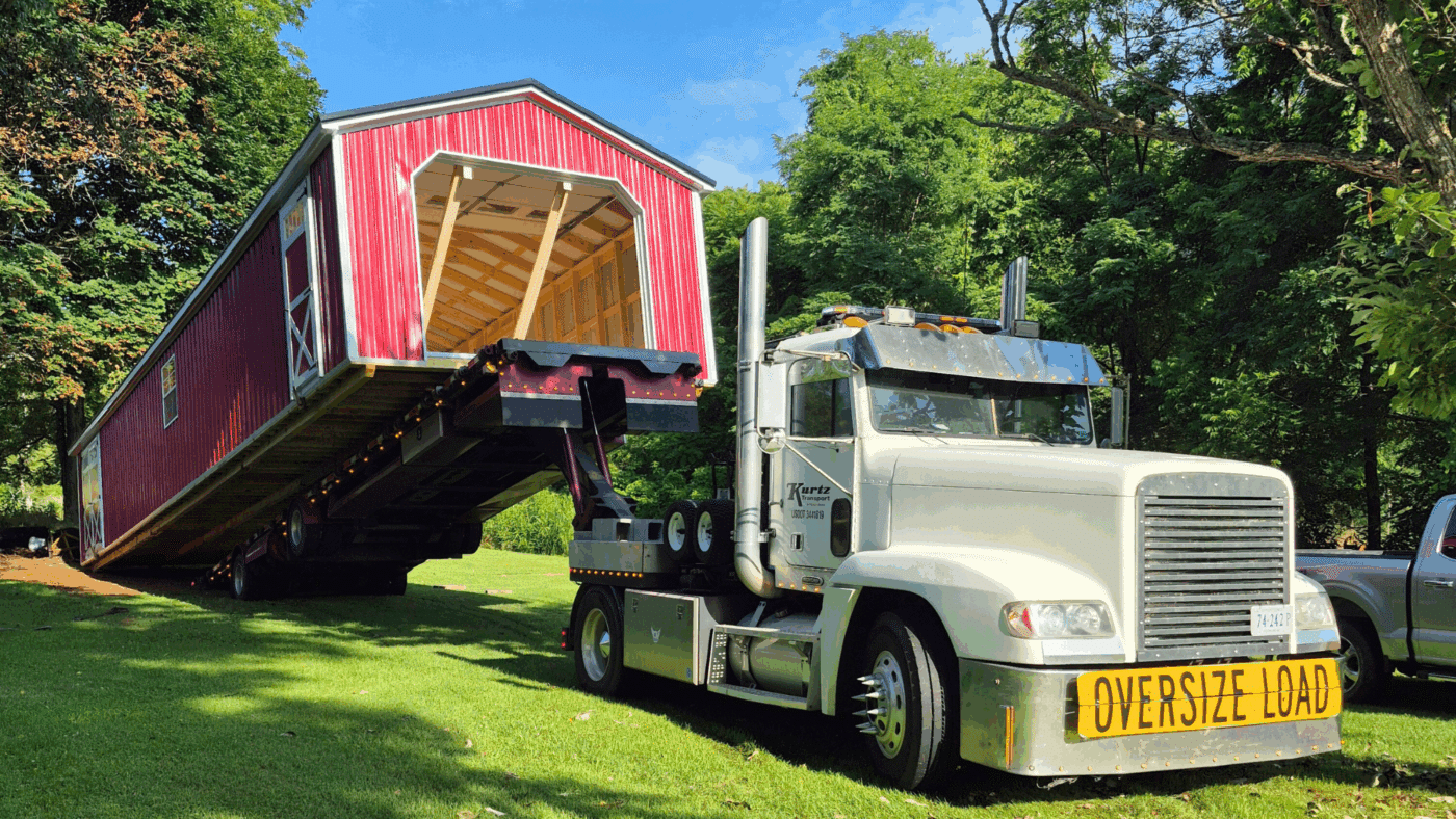 red 14x56 shed being delivered on the back of a truck